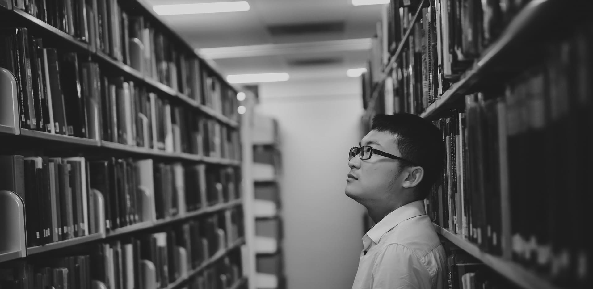 Man looking at a shelf of books for information on visas and migration