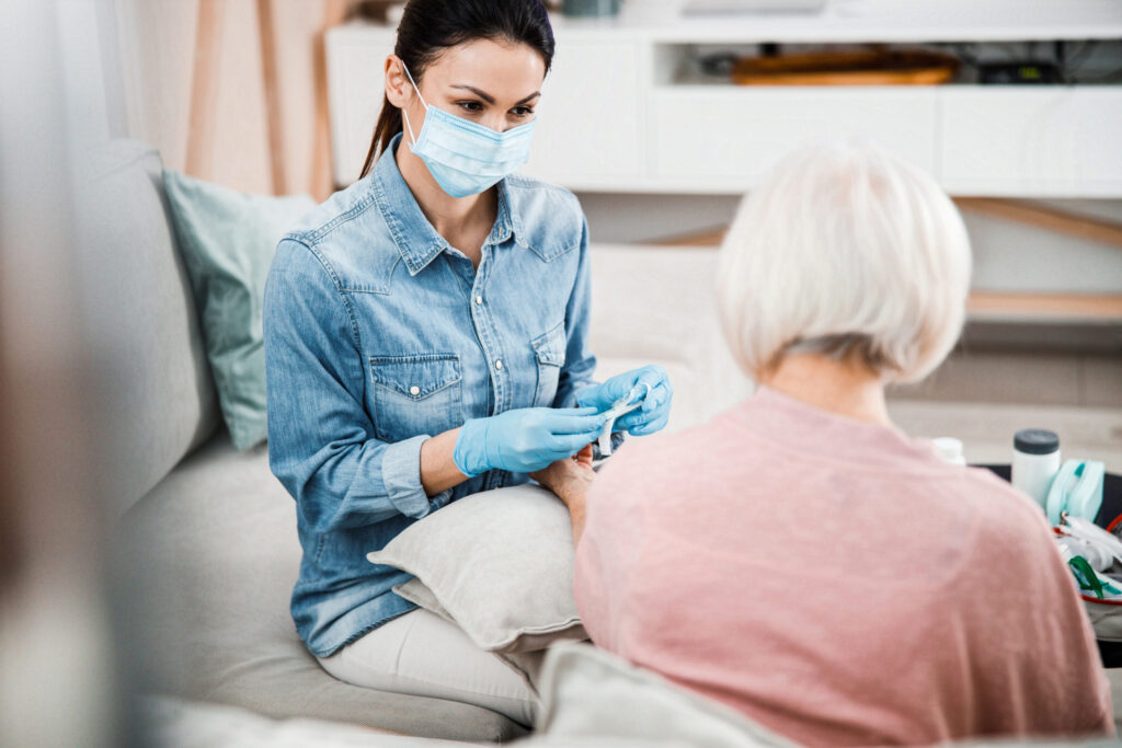 Female doctor sitting on couch with old woman