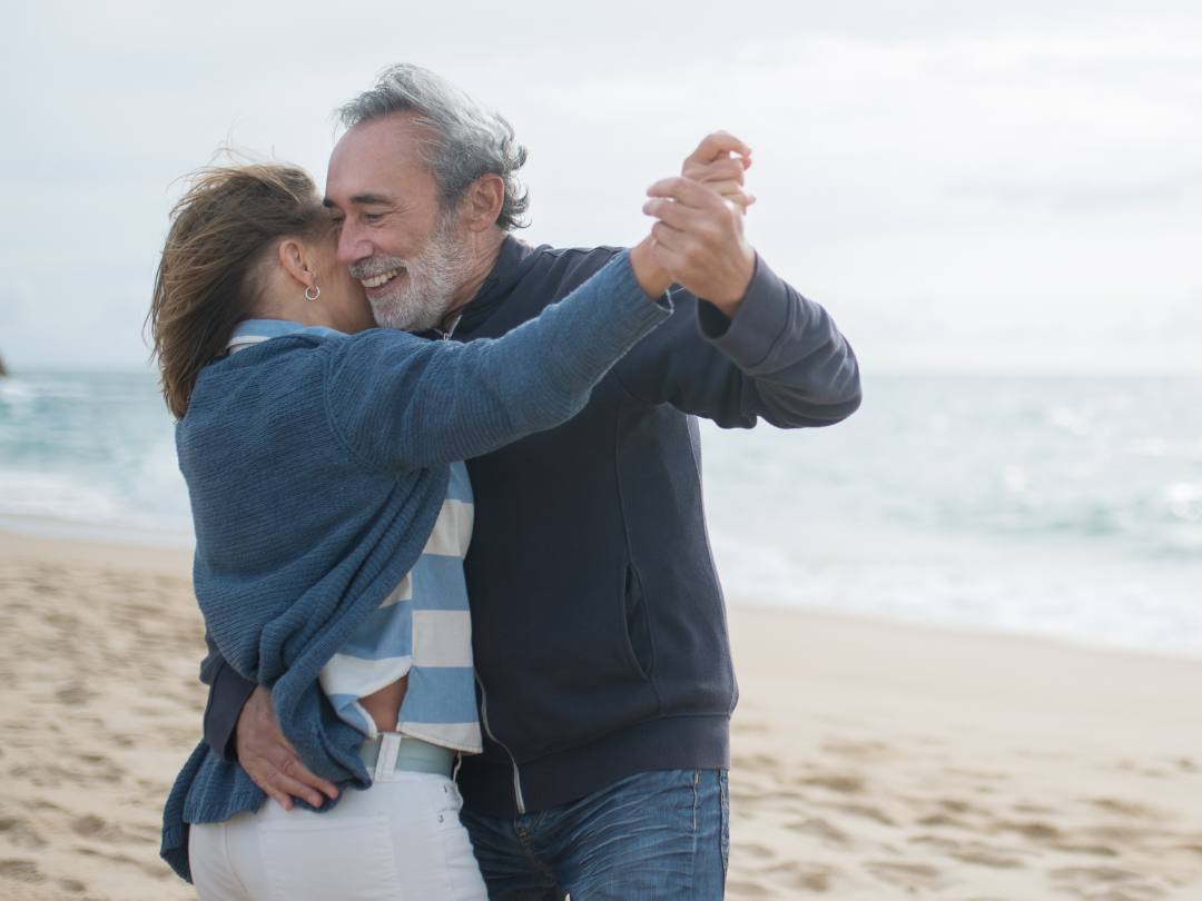 elderly couple dancing on the beach